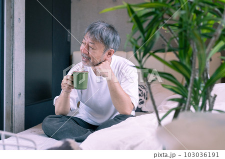 ベッドの上でコーヒーを飲むミドルエイジの男性 103036191