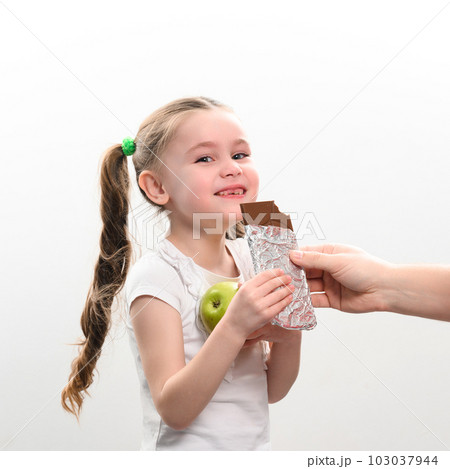 Portrait of a child with an apple and chocolate on a white background, green apple and milk chocolate. 103037944