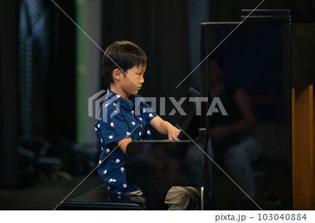 男の子がピアノ発表会で弾いている様子（横写真ズームアップ） 103040884