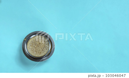 South Indian filter coffee cup on blue background. Top view with copy space South Indian filter coffee cup on blue background. Top view with copy space 103046047