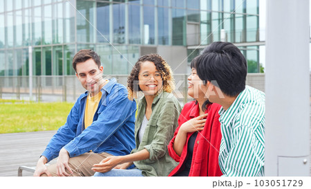 ベンチに座って話す多国籍学生グループ 103051729