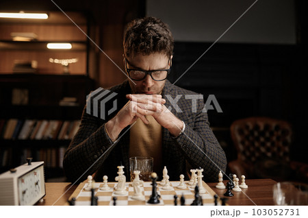 Focus on serious young man looking thoughtfully at chessboard pieces Focus on serious young man looking thoughtfully at chessboard pieces 103052731