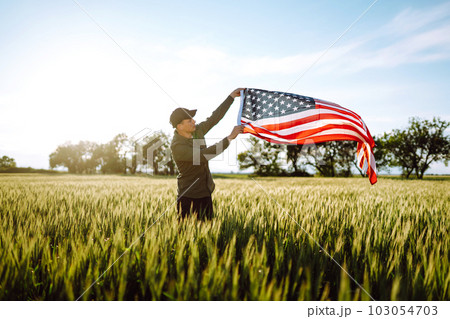Man hold waving american USA flag. Patriot raise national american flag. Independence Day, 4th July. 103054703
