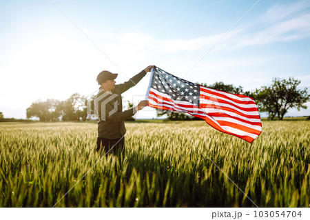Man hold waving american USA flag. Patriot raise national american flag. Independence Day, 4th July. Man hold waving american USA flag. Patriot raise national american flag. Independence Day, 4th July. 103054704