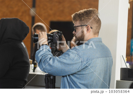 Man videomaker works on news conference modern video camera with a digital display recording an interview on event. Mass media and television and technology concept Man videomaker works on news conference modern video camera with a digital display recording an interview on event. Mass media and television and technology concept 103058364