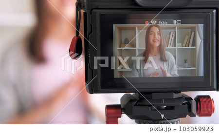 Online influencer. Live streaming. Woman blogger creating content shooting video for social media vlog using camera communicating with subscribers at home. Online influencer. Live streaming. Woman blogger creating content shooting video for social media vlog using camera communicating with subscribers at home. 103059923