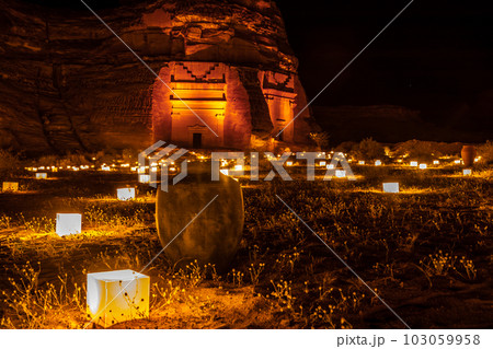 Old Amphora in front of ancient tombs of Hegra city illuminated during the night, Al Ula, Saudi Arabia 103059958