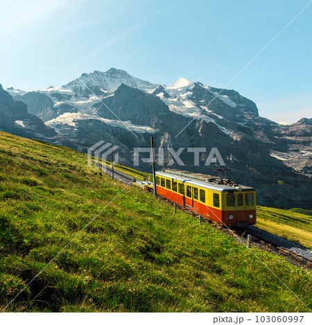Small retro tourist train and snowy mountains in background, Switzerland 103060997