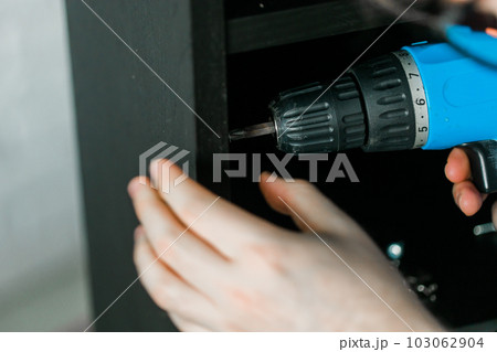 Master uses a cordless screwdriver to screw shelf close up - home improvement concept Master uses a cordless screwdriver to screw shelf close up - home improvement concept 103062904