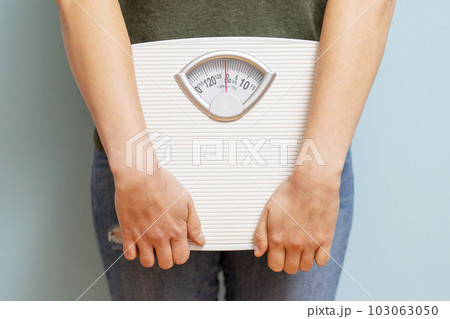 Young woman holding white scales to check the results of her diet 103063050