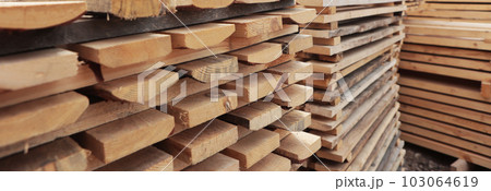 Stacked wooden boards in the woodworking industry. Stacks with pine lumber. Folded edged board. Wood harvesting workshop. Narrow banner. Stacked wooden boards in the woodworking industry. Stacks with pine lumber. Folded edged board. Wood harvesting workshop. Narrow banner. 103064619