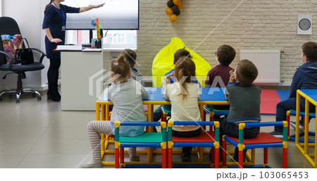 The teacher conducts a lesson for a group of preschoolers in a children's educational center. The teacher conducts a lesson for a group of preschoolers in a children's educational center. 103065453