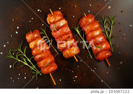 Fresh raw marinated skinless chicken leg meat skewers with fresh herbs on a black background.Top view.Copy space.Closeup of chicken meat.Procurement for designers. Fresh raw marinated skinless chicken leg meat skewers with fresh herbs on a black background.Top view.Copy space.Closeup of chicken meat.Procurement for designers. 103067122