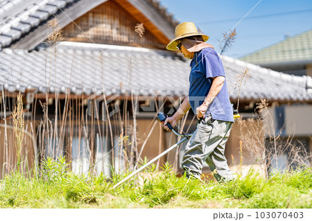 初夏に草刈り機で草刈りをする高齢男性 103070403