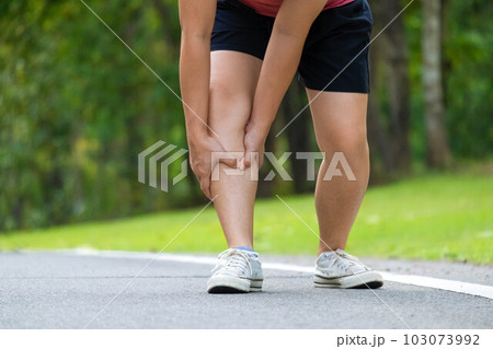 Close-up of young female athlete having knee pain after exercise. Female athlete having leg pain while exercising in park. Exercise injury concept 103073992
