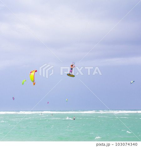 Kiteboarding. Fun in the ocean. Extreme Sport Kitesurfing. Kitesurfer jumping high in the air performing triks during kitesurfing session Kiteboarding. Fun in the ocean. Extreme Sport Kitesurfing. Kitesurfer jumping high in the air performing triks during kitesurfing session 103074340