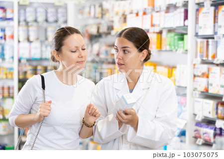 Woman pharmacist helping woman customer to choose remedy in pharmacy Woman pharmacist helping woman customer to choose remedy in pharmacy 103075075