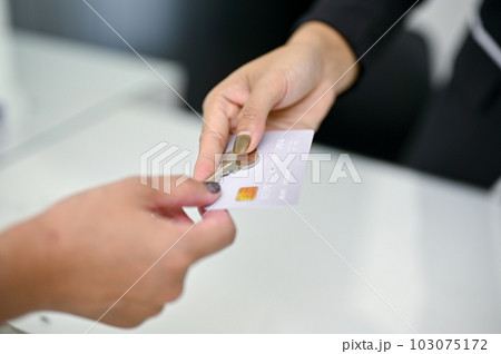 Close-up image of a receptionist giving a credit card and a room key to a customer 103075172