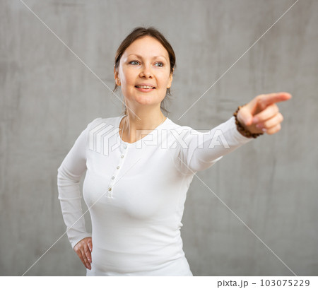 Cheerful woman with wide grin on her face exuding happiness and positivity pointing Cheerful woman with wide grin on her face exuding happiness and positivity pointing 103075229