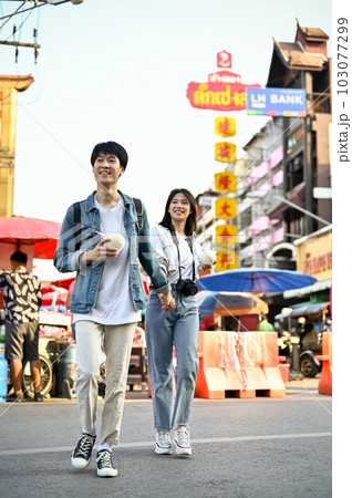 A tourist couple holding hands while crossing the street, enjoys sightseeing 103077299