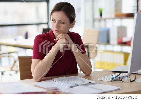 Doubting woman thinks about work looking away in office Doubting woman thinks about work looking away in office 103077953