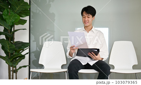 Smart Asian male candidate sits in a waiting room, waiting for a job interview. 103079365