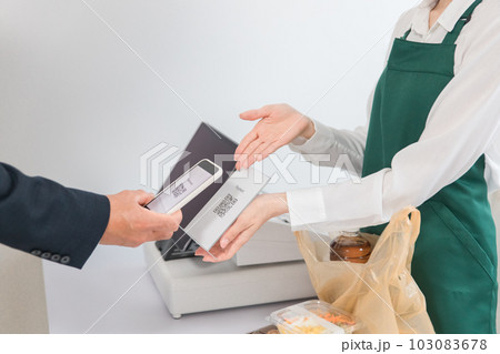 コンビニでスマートフォンを使ってQRコード決済するビジネスマン 103083678