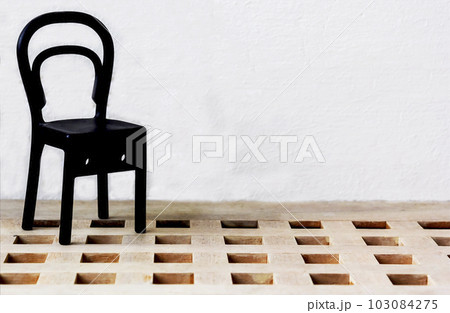 A small plastic chair stands on a parquet floor and a white background A small plastic chair stands on a parquet floor and a white background 103084275