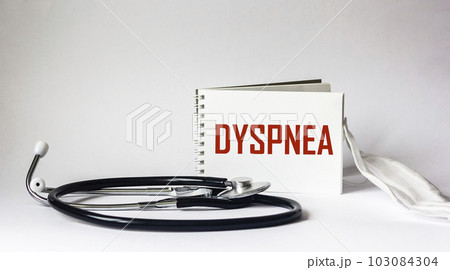 On a white background, a stethoscope, a medical mask and a notepad with the word Dyspnea On a white background, a stethoscope, a medical mask and a notepad with the word Dyspnea 103084304