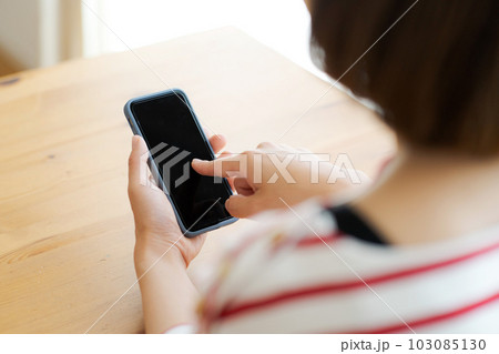携帯電話を操作する主婦の手元写真 103085130