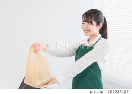 客にお弁当・商品を渡す笑顔の女性店員 客にお弁当・商品を渡す笑顔の女性店員 103087127