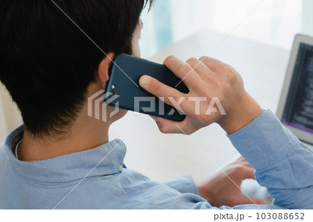 スマホでシステムメンテナンスの打合せをする男性 103088652