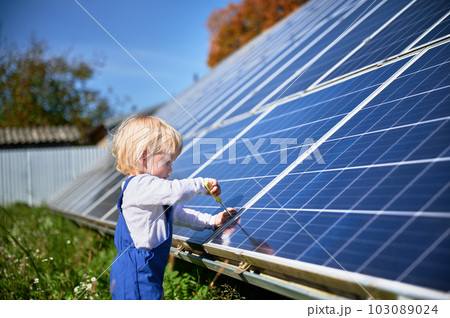 Boy learning how does solar panel work. Small kid interested in using different tools. Curious boy helping to tighten the screw. 103089024