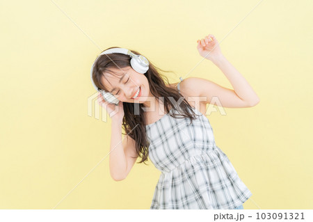 イエローバックでヘッドホンで音楽を聴く若い女性 イエローバックでヘッドホンで音楽を聴く若い女性 103091321