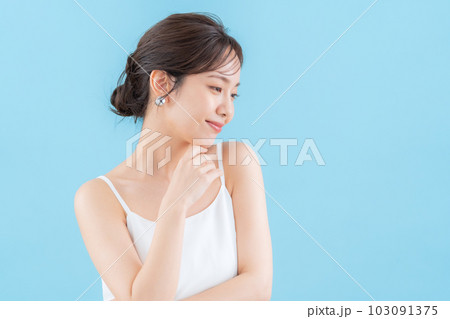 ブルーバックでスキンケアをする若い女性 103091375