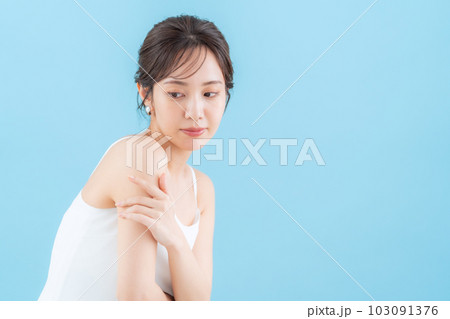 ブルーバックでスキンケアをする若い女性 103091376