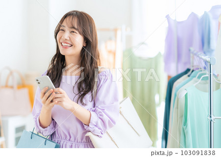お店でショッピングしながらスマホを操作する若い女性 103091838
