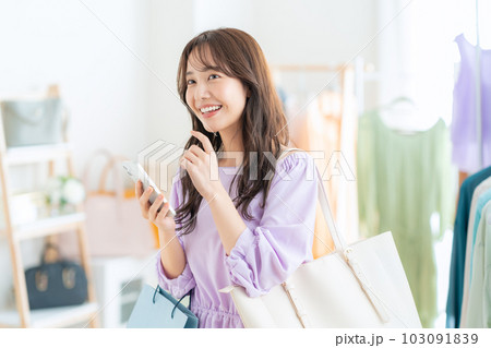 お店でショッピングしながらスマホを操作する若い女性 103091839