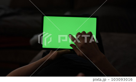 Man at home lying on a couch with tablet pc with green screen Man at home lying on a couch with tablet pc with green screen 103093016