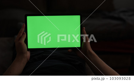 Man at home lying on a couch with tablet pc with green screen Man at home lying on a couch with tablet pc with green screen 103093028