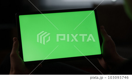 Man at home lying on a couch with tablet pc with green screen 103093746