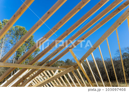 This is new building under construction with trusses and roof beams supported by wooden joists 103097408