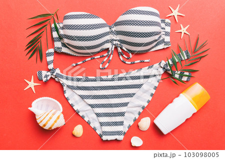 Woman swimwear and beach accessories flat lay top view on colored background Summer travel concept. bikini swimsuit, straw hat and seasheels. Copy space Top view 103098005