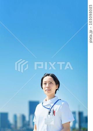 晴天の街並みの前に立つ白衣の女性 103098085