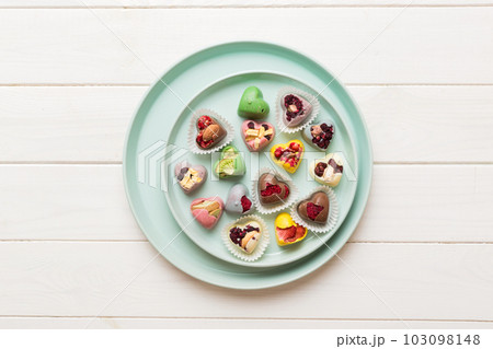 Plate with different chocolate on colored background. Assortment of fine chocolates top view vith copy space Health and obesity concept Plate with different chocolate on colored background. Assortment of fine chocolates top view vith copy space Health and obesity concept 103098148