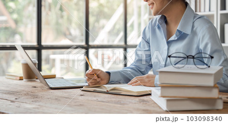 Young woman student busy study make notes in notebook and using laptop concentrated online training course technology education 103098340