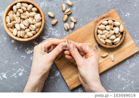 Woman hands holding a wooden bowl with pistachios nuts. Healthy food and snack. Vegetarian snacks of different nuts Woman hands holding a wooden bowl with pistachios nuts. Healthy food and snack. Vegetarian snacks of different nuts 103099019