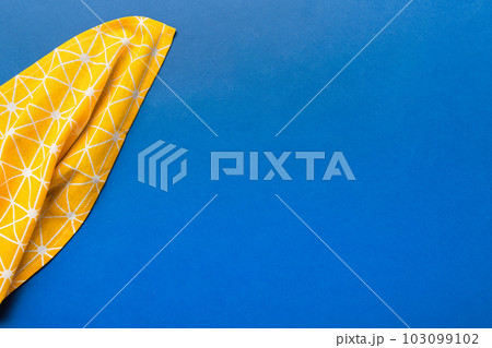top view with yellow empty kitchen napkin isolated on table background. Folded cloth for mockup with copy space, Flat lay. Minimal style 103099102