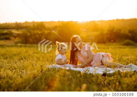 Mother and little daughter playing together in summer sunset. Happy mom with small child having fun. Mother and little daughter playing together in summer sunset. Happy mom with small child having fun. 103100109