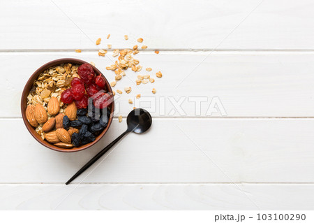 Cooking a wholesome breakfast. Granola with Various dried fruits and nuts in a bowl. The concept of a healthy dessert. Flat lay, top view with copy space Cooking a wholesome breakfast. Granola with Various dried fruits and nuts in a bowl. The concept of a healthy dessert. Flat lay, top view with copy space 103100290